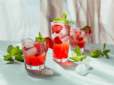 Bir bardak çilek kokteyli ya da mocktail, ezilmiş buz ve hafif arkaplanda köpüklü su ile ferahlatıcı bir yaz içeceği. İçecek fotoğrafçılığı.