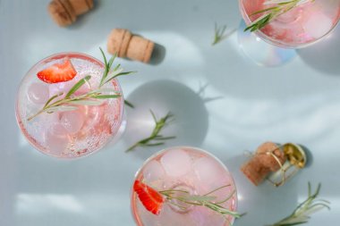 Bir bardak çilek kokteyli veya mocktail, ezilmiş buz ve açık mavi zemin üzerinde köpüklü su ile ferahlatıcı bir yaz içeceği. İçecek fotoğrafçılığı.