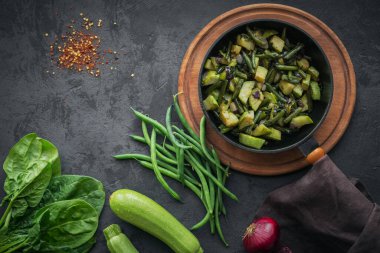 Sağlıklı kahvaltı masası, tavada kızarmış sebzeler ve siyah arka planda yemek pişirmek için gereken malzemeler fotokopi alanı. Karnabahar, kabak, ıspanak yaprağı ve yeşil fasulye.