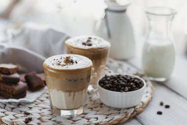 Dalgona kremalı kahve, hazır, kremalı, buzlu kahve. Hafif arka planda kahve, süt ve buz parçalı kokteyl hazırlandı. Metin için kopyalama alanı olan modaya uygun içecek arkaplanı.