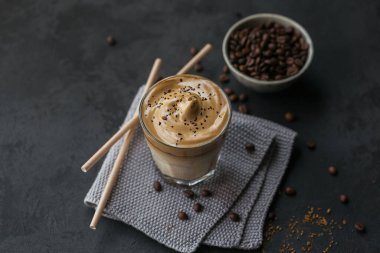 Dalgona kremalı kahve, hazır, kremalı, buzlu kahve. Siyah arka planda kahve, süt ve buz parçalı kokteyl. Metin için kopyalama alanı olan modaya uygun içecek arkaplanı.