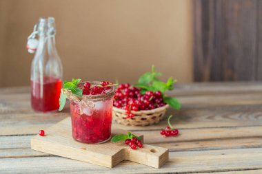 Bir bardak kırmızı frenk üzümü kokteyli ya da moktail, ezilmiş buz ve ahşap zemin üzerinde köpüklü su ile ferahlatıcı yaz içeceği..