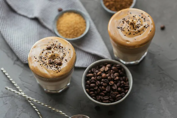 Склянка кави Iced Dalgona, модна пухнаста вершкова збитих кави та молока на сірому фоні . — стокове фото