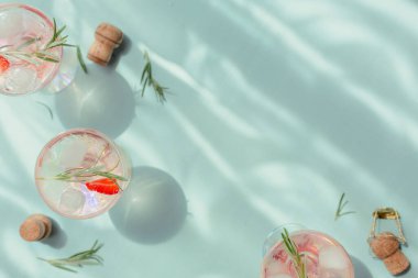 Taze çilek kokteyli. Açık mavi arka planda çilekli, biberiyeli ve buzlu pembe yaz kokteyli. Metin için kopyalama alanı olan moda gölgeler ve güneş ışığı arkaplanı.