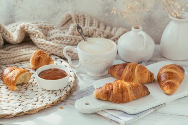 Taze kruvasanla nefis bir kahvaltı ve beyaz ahşap arka planda reçelle servis edilen bir fincan kahve. Lezzetli Pişirme