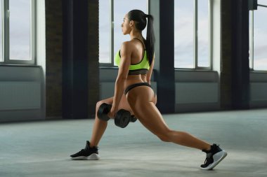 Atletik kız fallouts dumbbells ile gerçekleştirme.
