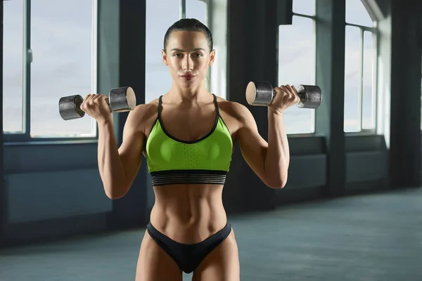 Woman bodybuilder lifting metallic dumbbells. — Stock Photo, Image