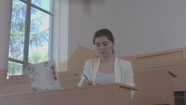 Feliz chica sonriente con anteojos sentados en el aula . — Vídeo de stock