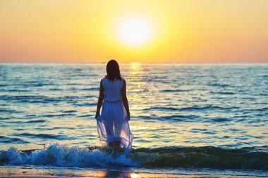 Dalgalar deniz yürüme beyaz elbiseli bir kız Backview.