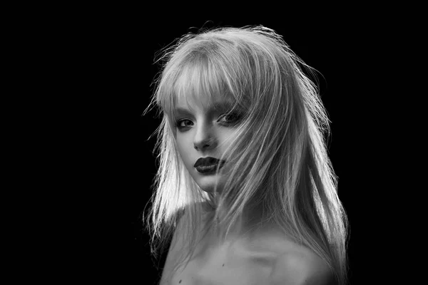 Black and white photo of model with blonde dishevelled hair, opened shoulders.