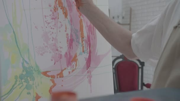 Artista tirando tinta laranja de uma garrafa com seu pincel — Vídeo de Stock