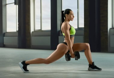 Atletik kadın dumbbells ile hızlı düşük fallouts gerçekleştirme.