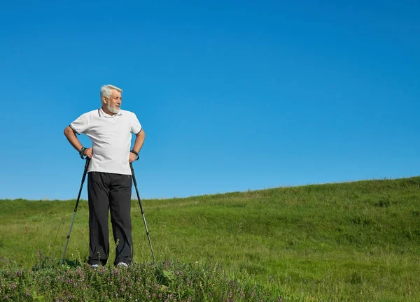 Αθλητής που στέκεται με παρακολούθηση μπαστούνια σε καταπράσινο λόφο. — Φωτογραφία Αρχείου