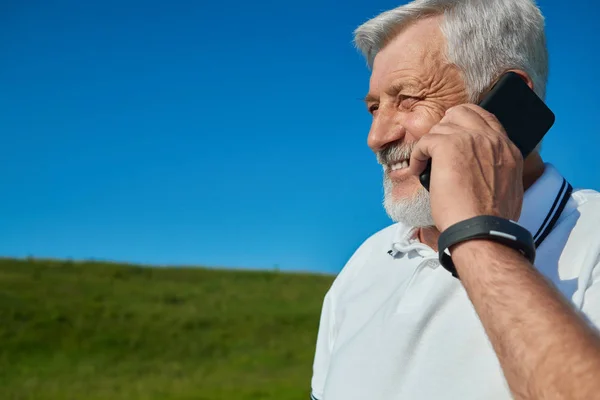 Tersenyum orang tua berbicara pada ponsel di lapangan . — Stok Foto