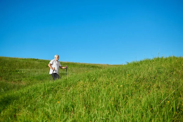 Wandelen met stokken tracking op frisse lucht tussen met gras begroeide heuvels. — Stockfoto
