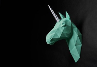 Origami mat yeşil tek boynuzlu atlara kafa siyah duvarda asılı.