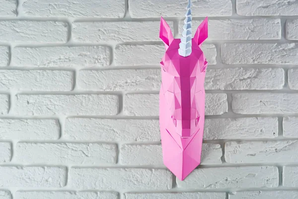 粉红色的独角兽头用纸挂在白砖墙上. — 图库照片