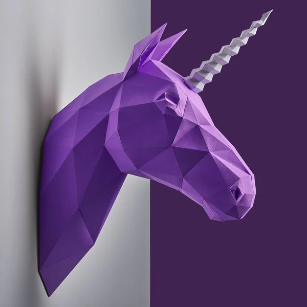 Bright photo of violet unicorns head made of paper hanging on grey wall. — Stock Photo, Image