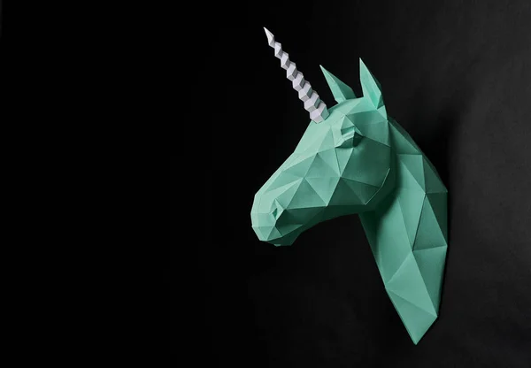Origami dull green unicorns head hanging on black wall. — Stock Photo, Image