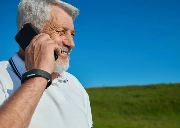 Orang tua berbicara pada ponsel di lapangan . — Stok Foto