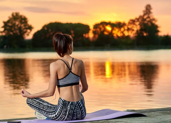 Backview di jogging ragazza vicino lago al tramonto . — Foto Stock