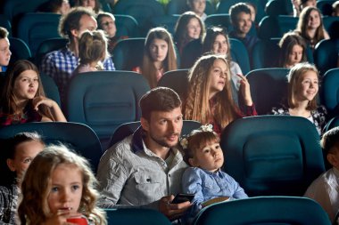 Çizgi film izliyor ve sinemada gülümseyen genç izleyiciler.