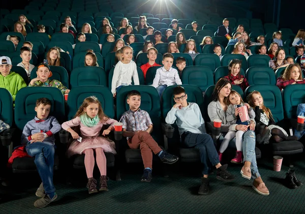 Crowd of viewers sitting in movie theatre and watching cartoon.