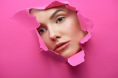 Güzel kızların yüzüne delik yırtılmış pembe karton.
