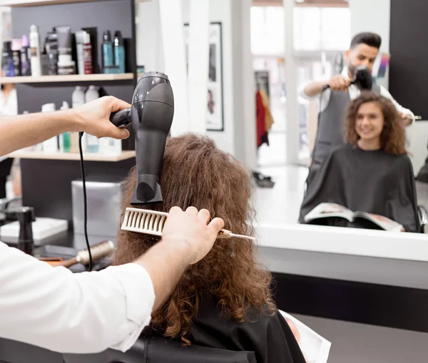 Backview του hairstyler ξήρανση γυναίκες πελάτες σγουρά μαλλιά. — Φωτογραφία Αρχείου