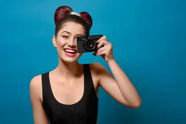 Smiling, happy girl taking photo with old camera.