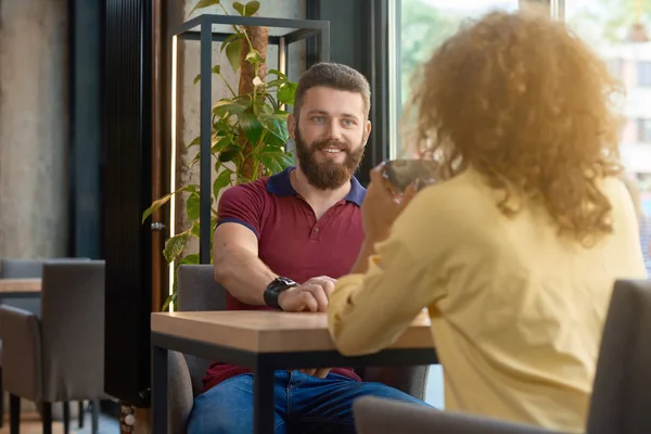 Smiling man with beard looking at girl sitting in font of him.