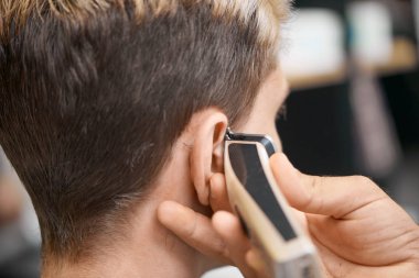 Berberler el kullanarak saç kesme makinesi, istemci için yeni saç kesimi yapıyor.