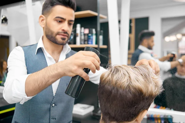 Doing new hairstyle for male model using hairspray.