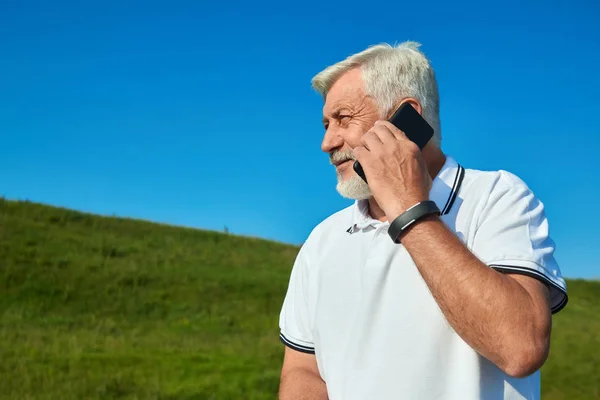 Sideview vanha mies puhuu kännykkään kun kesäpäivä . — kuvapankkivalokuva