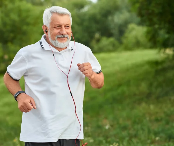 Θετική τρέχοντας γέρος σε καταπράσινο πάρκο. — Φωτογραφία Αρχείου