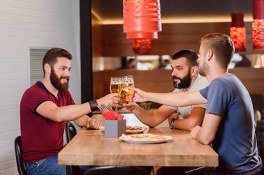 Üç arkadaş pizzacı bira bardakları tokuşturup.