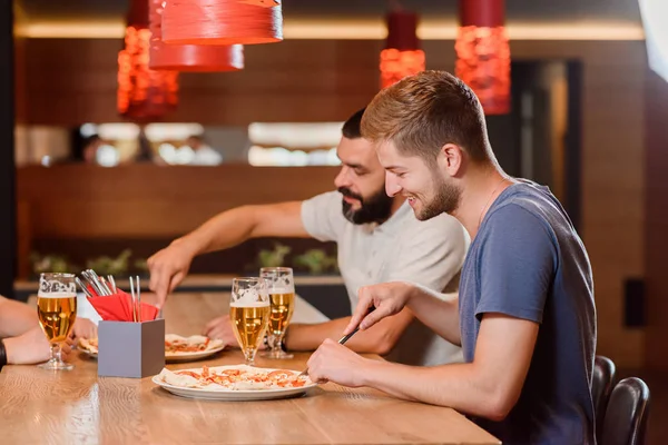Dois amigos comendo pizza usando faca e garfo . — Fotografia de Stock