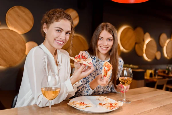 Splendide donne che sorridono, posano e mangiano pizza in pizzeria . — Foto Stock