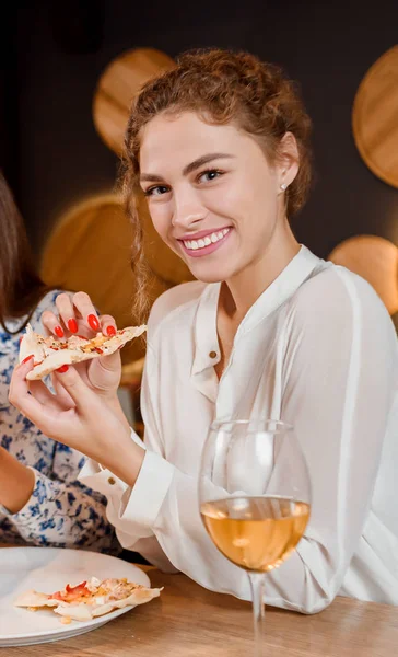 Belle femme assise au restaurant et mangeant une pizza appétissante . — Photo