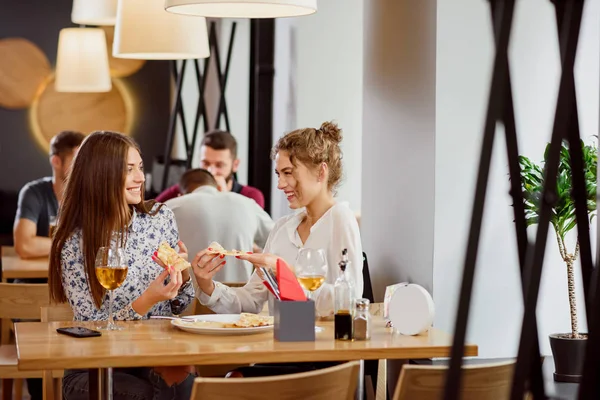 Positiva kvinnliga vänner chatta och äta på pizzerian. — Stockfoto