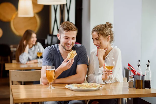 Süßes Paar isst Pizza und trinkt Bier und Wein in Pizzeria. — Stockfoto