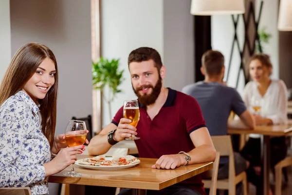 Schönes Paar hält Glas Wein und Bier in Pizzeria. — Stockfoto