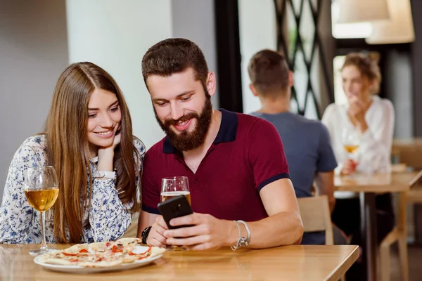 Paar sitzt in Pizzeria mit Pizza, Wein und Bier. — Stockfoto