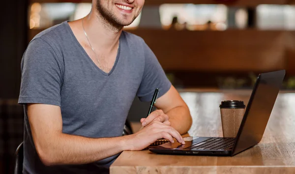 Улыбающийся человек пьет кофе и работает в кафе . — стоковое фото