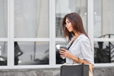 Çantaları taşırken dükkandan çıkıyor uzun esmer saçlı Genç ince kız.