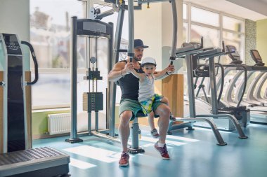 Baba eğitim el uygun ve küçük oğlu dizlerinin üzerinde tutarak simülatör geri.