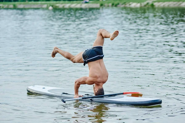 Permanent op hoofd, yoga oefeningen, zwemmen op sup boad in stad meer doen. — Stockfoto