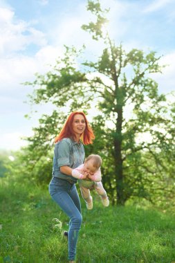 Kızıl saçlı küçük kızı bahçede oynayan genç gülmek anne.