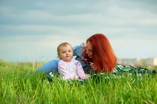 Mladá maminka hraje se svou malou dcerou na trávě. — Stock fotografie