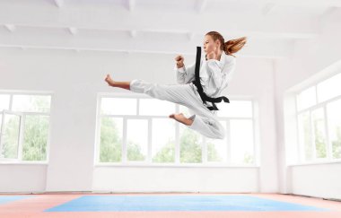 Siyah atlama ve tekme gerçekleştirme kemer ile beyaz kimono kadında.